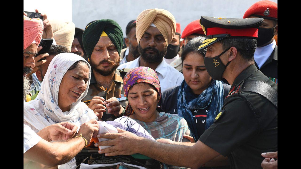 An army officer gives an Indian national flag and an army uniform to Mandeep Kaur (C), wife of slain Indian Army soldier Mandeep Singh. Pic/AFP